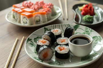Set sushi roll California and sushi Maki with salmon on a wooden table. Asian food Sushi and soy sauce in a bowl, ginger and lemon. Sushi menu. Japanese food. hand-made fresh sushi rolls