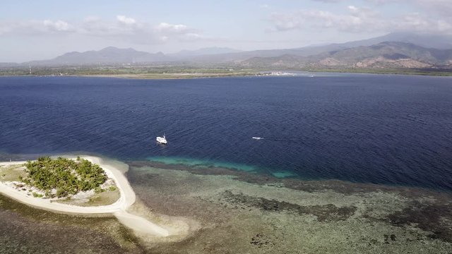 Tourist boat anchored next to Pulau Bedil, a tiny Indonesian beautiful island off the coat of Lombok, Aerial view.