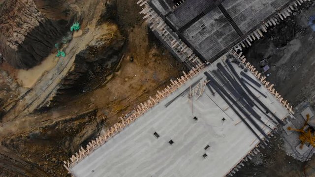 Excavated ground on construction site with new residential buildings under yellow crane, drone footage