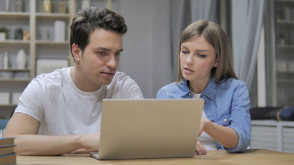 Young Casual Designers Discussing Project and Working On Laptop