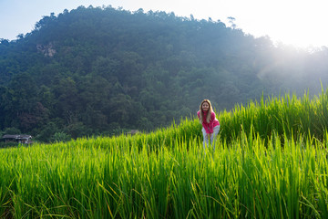 Asian woman in pink sweater standing in green rice terrace