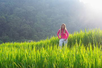 Asian woman in pink sweater smiling in green rice terrace
