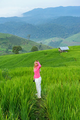 Thai woman standing in green rice field with mountain background