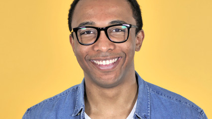 Close Up of Smiling African Man in Glasses Isolated on Yellow Background