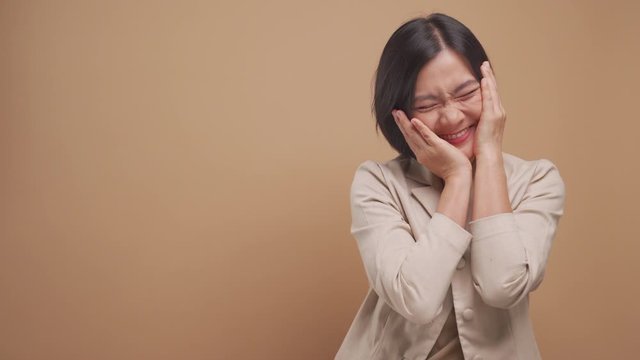 Happy asian business woman feel shy standing with copy space isolated over beige background. 4K video
