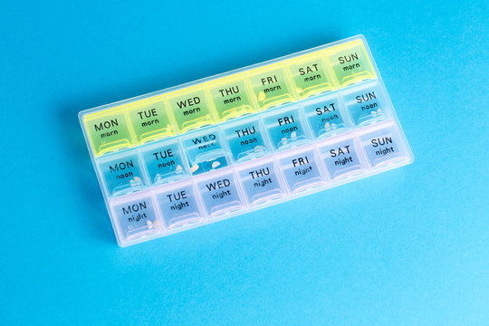 Organizer for medical pills on a blue isolated background close-up. Organization of taking pills of the day.