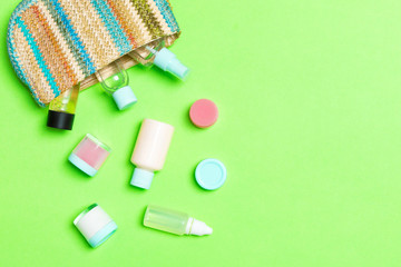 Woman cosmetic bag with set of beauty product and bodycare cream on green background with copy space for you design