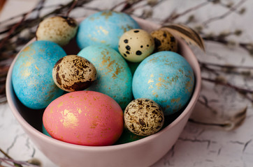Easter colorful eggs in the plate and  willow branch on white background. Easter holiday postcard concept. Copy space for text.