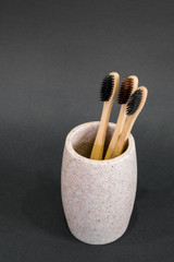 Eco toothbrushes in a glass on grey background