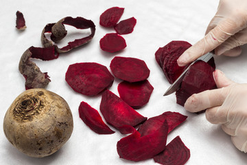 Hands in gloves slice beets.