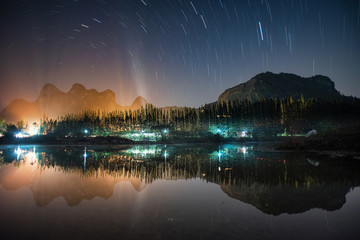 Beautiful Star trails over mountain with reflection on lake at Khao e bid