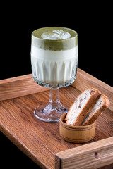 Matcha latte in a glass with almond crackers, on a dark background
