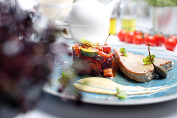 Tuna steak with fried vegetables. A plate with an appetizing dish. Application suggestion. Culinary photography, food stylization.