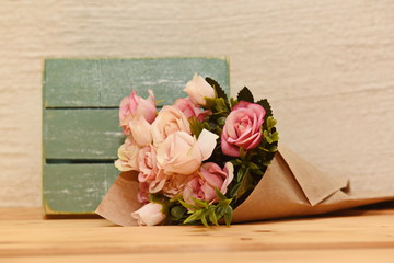 artificial roses in craft paper on the background of a wooden box