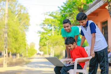 Cute little Indian/Asian boy studying or playing game with laptop computer