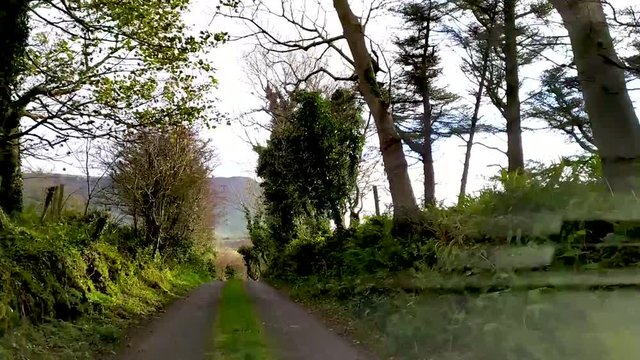Dashcamera video with view on road with trees and benbulbin mountain