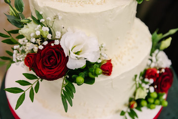 Decorated with red roses and white tsetets wedding cream three-tier cake