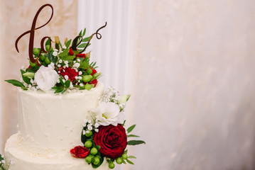 Wedding cake decorated with red roses and the inscription love. Place for text