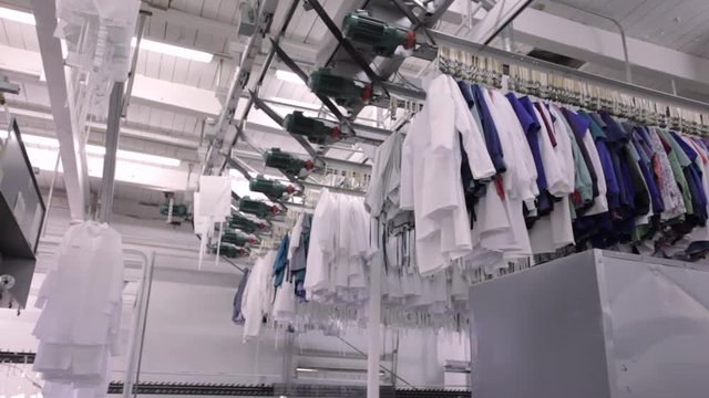 Lab coats and other laundry moving on an industrial ceiling conveyor.