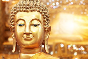 Golden buddha face on golden background at Thai temple.
