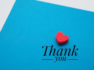  The words thank you and the red heart on the blue paper background.