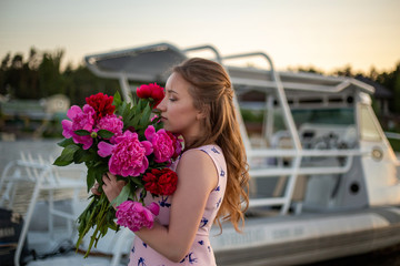 horizontal profile portrait of a young blonde with a bouquet of peonies on a yacht background