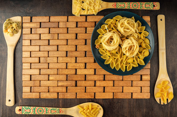 blue ceramic bowl with fettuccine paste on a bamboo backing and on a wooden background with bamboo blades