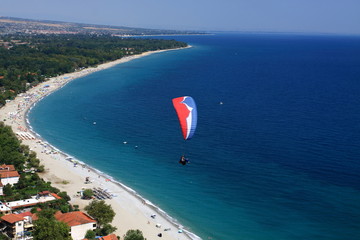 Paragliding over a bay in the Aegean Sea. View of the blue surface of the water from the height of...