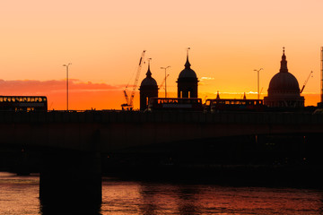 Sunset forming a silhouette of London cityscape including London Bridge, Cannon Street station and double decker buses