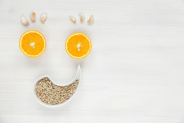 Smiley face made of fruit and nuts. Happy face is made from oranges garlic and sunflower seeds. Natural useful products antiviral drugs for health, immunity and fight against the virus.