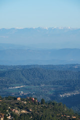 Fototapeta na wymiar Distant snowy mountains seen from an elevated mountain village, Montserrat, Catalonia