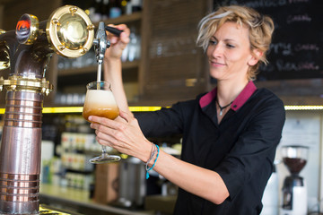 Bartender woman serving beer.
