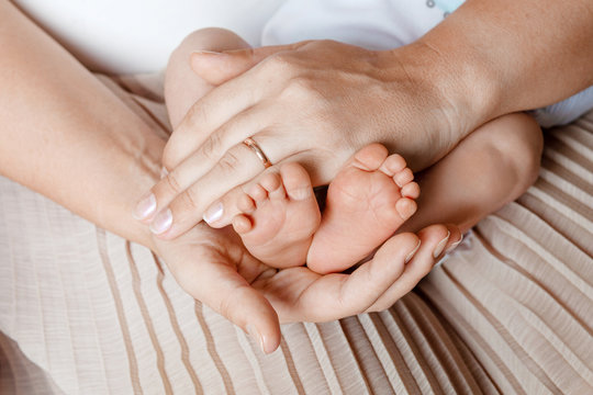 Baby feet in mother hands. Tiny newborn baby's feet on female shaped hands closeup. Mom and her child. Happy Family concept. Beautiful conceptual image of Maternity