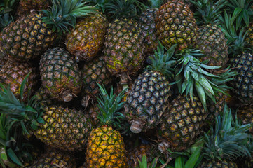 Plenty of fresh pineapple fruits on a counter in a market