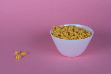 White plate with Breakfast cereals on a pink background. side view.