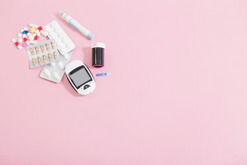 glucometer and pills on  pink background