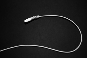 Close-up of white USB type-c charge connector with cable protection on black background.