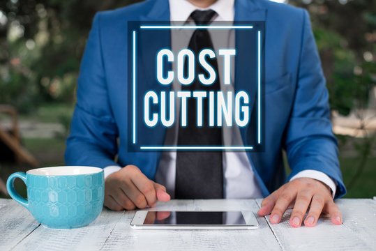 Writing note showing Cost Cutting. Business concept for actions taken to reduce the amount that is spent on a service Businessman with pointing finger in front of him