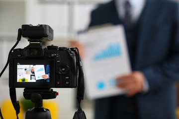 Male in suit and tie show stats graph pad making promo videoblog or photo session in office camcorder to tripod closeup. Vlogger selfie sale solution or finance advisor management information © H_Ko