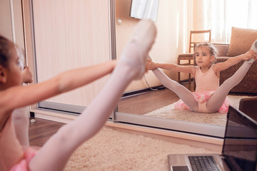Young ballerina practicing classic choreography during online class in ballet school, self-isolation