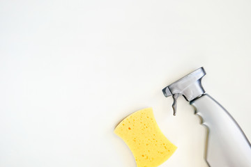 Cleaning agent in a spray in a gray bottle. Top view of cleaning product and sponge on white background. Closeup. Copy space.