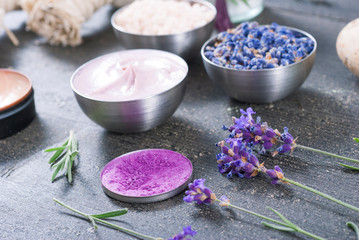 Obraz na płótnie Canvas beauty product samples with fresh purple and blue dried lavenders, bath salts and massage pouches on dark wood table background