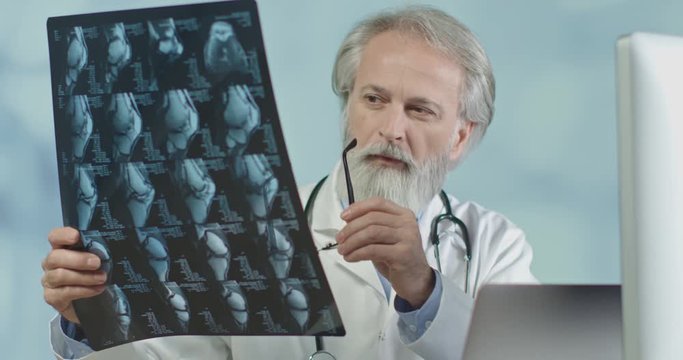 Close up of a medical doctor in his office looking at x-ray and ct scans. Corona infection
