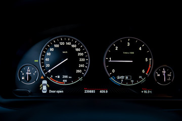 Car dashboard with speedometer, tachometer, clock, fuel tank gauge, oil temperature and display with on-board computer and black odometer with white arrows and divisions. Auto service industry.