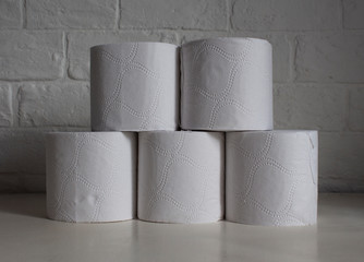 Tower of rolls of toilet paper on a white wall background.