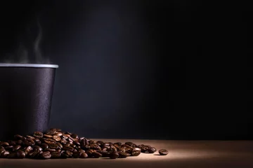 Crédence en verre imprimé Café Tasse de café jetable noire avec de la fumée et des grains de café éparpillés sur fond sombre. Espace pour le texte