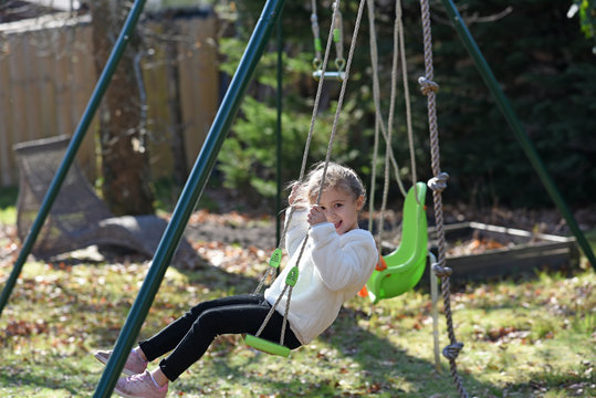 blonde girl on a swing with white sweater in profile