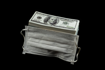 Doctor mask and virus protection and money a stack of 100 US dollars banknote a lot of at the black...