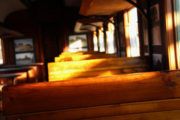 Old wagon interior made of wood. Wooden chairs in aged train wagon. Abstract travelling background.