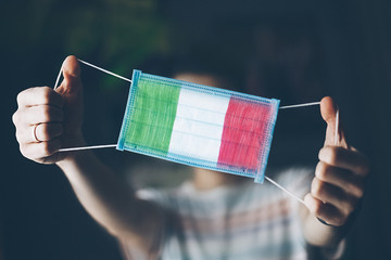 medical mask in hands of man, with the flag of  Italy painted. Copy space